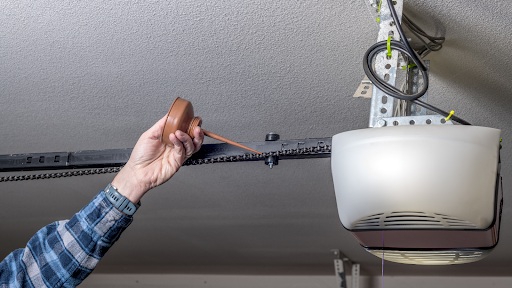 Close-up of a garage door spring being lubricated for maintenance, extending its lifespan. Expert service by MN Garage Squad